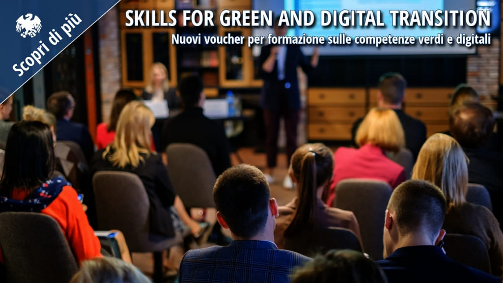 Aula formativa con partecipanti seduti e formatore sul palco durante un seminario dedicato alla transizione verde e digitale.