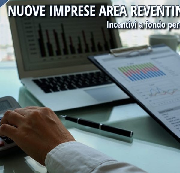 Imprenditore analizza dati economici su laptop e documenti per avvio nuova impresa con incentivi in Calabria.